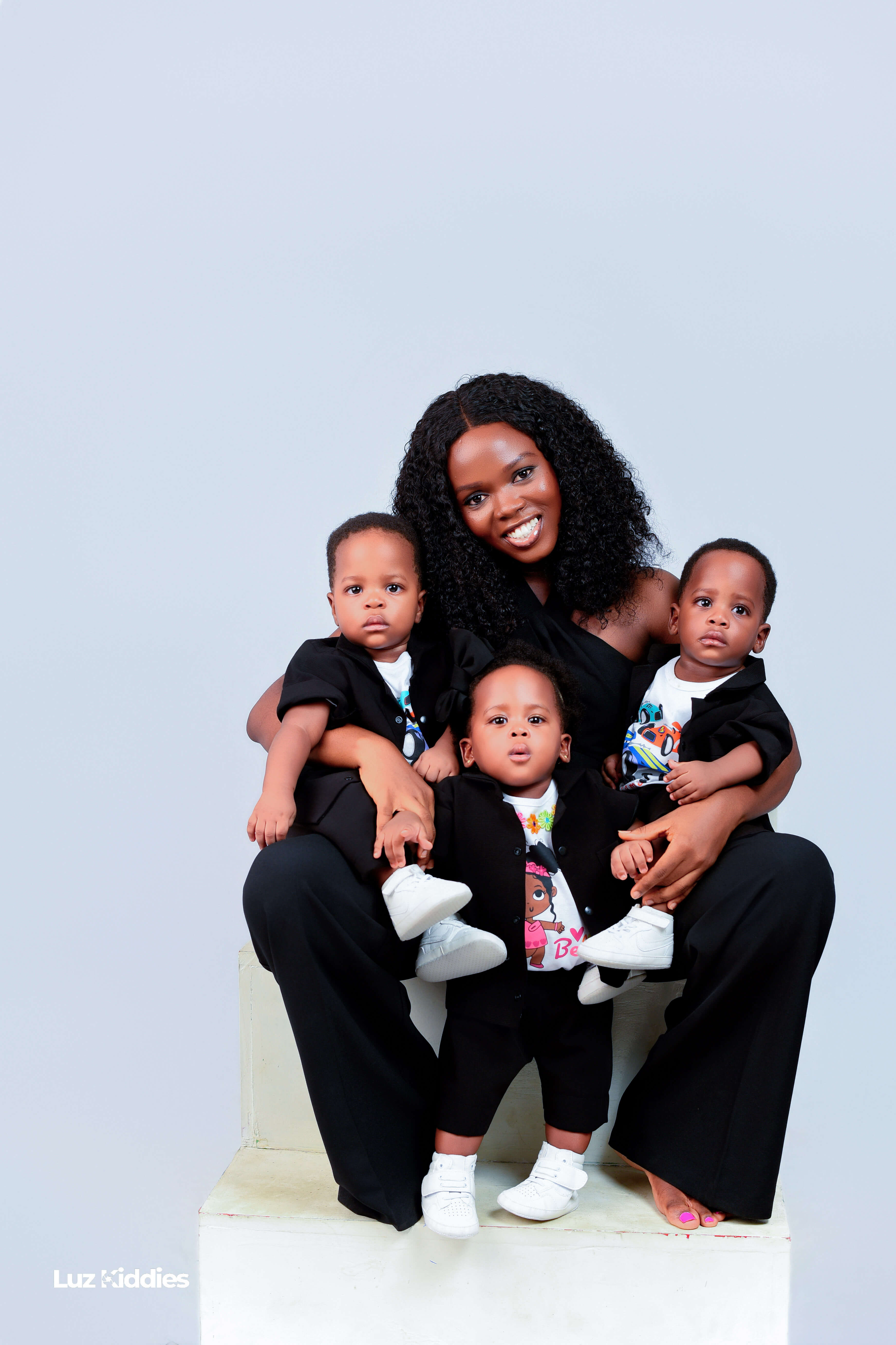 A Triplet mom carrying two boys and a girl in her arms.