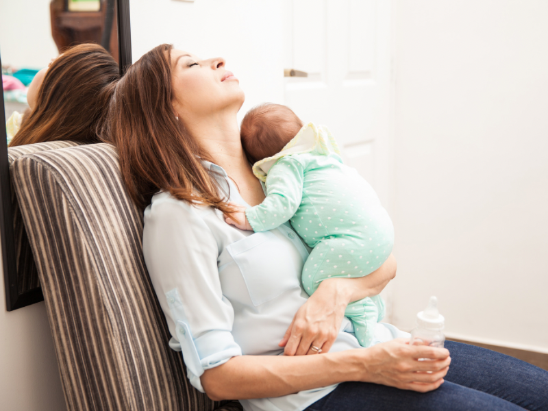a mom carrying her baby with a bottle in hr hand